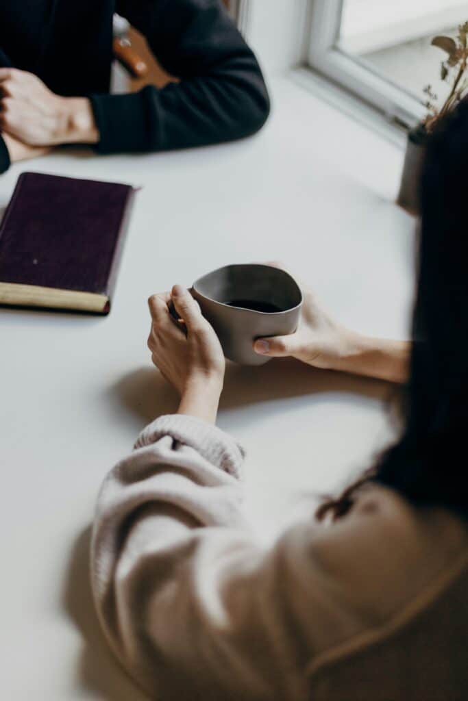 Person holding a warm cup during a supportive conversation in a Christian counseling setting
