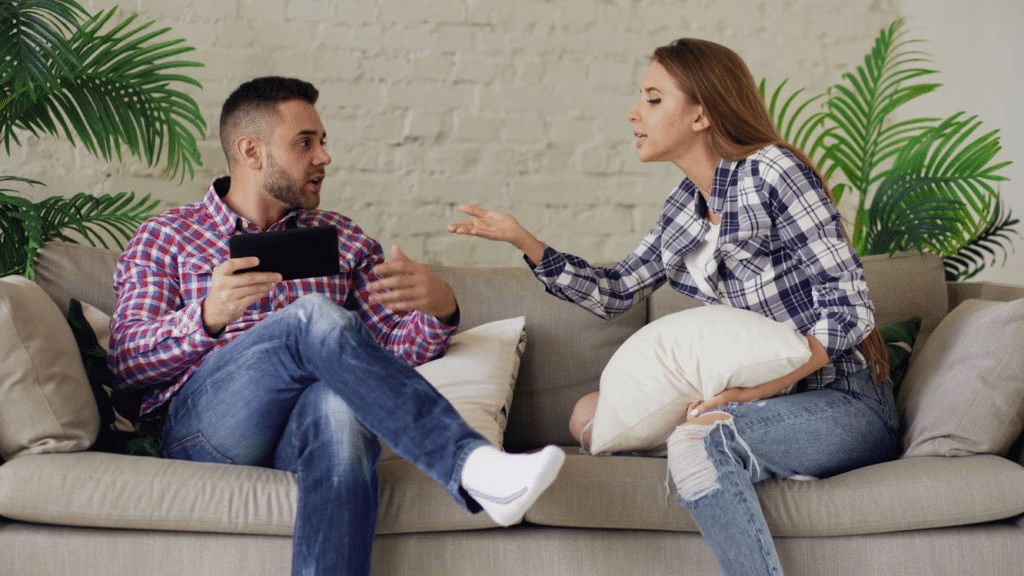 Couple sitting on a couch having a tense conversation, illustrating communication struggles in relationships